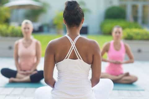Yoga instructor leading outdoor class with participants on mats in front of residential homes
