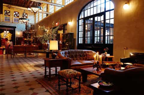Elegant hotel lobby with leather furniture, fireplace, and arched windows