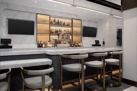 Contemporary bar lounge with marble walls, illuminated bottle display, and bar seating