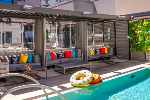 Contemporary poolside cabanas with gray sofas, colorful pillows, and modern pergola structure