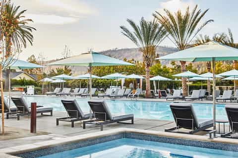 Large resort pool with loungers, umbrellas, and mountain views surrounded by palm trees
