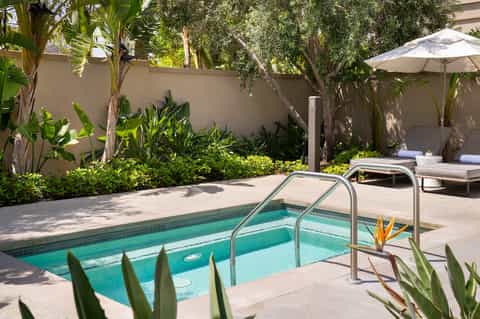 Spa hot tub with turquoise water surrounded by lush tropical plants and white umbrella