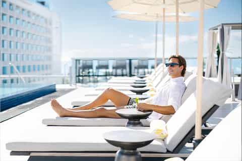 Man relaxing on lounge chair at rooftop pool deck