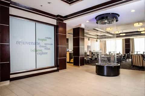 Modern hotel entrance with inspirational words on glass doors, cylindrical water feature, and contemporary design