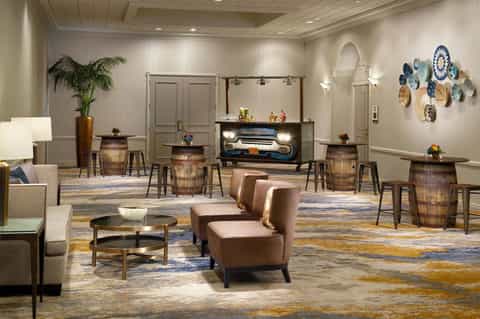 Modern hotel lobby with leather seating, wooden barrel tables, decorative plates, and contemporary furnishings