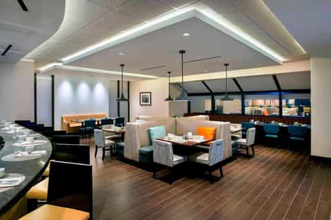 Modern restaurant interior with booth seating, pendant lighting, and ocean-view windows