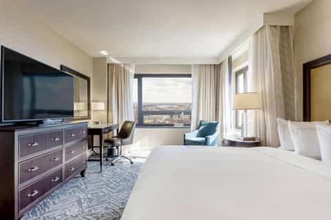 Luxury hotel suite with panoramic city view, work desk, contemporary furnishings, and elegant decor