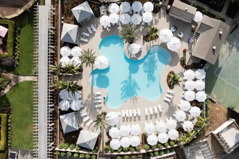 Aerial view of resort pool complex with white umbrellas and loungers