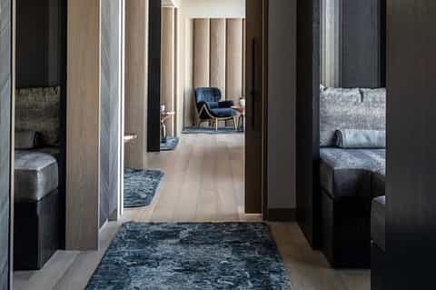 Modern hallway with dark wood doors, neutral walls, and contemporary furnishings visible through openings