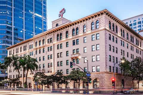 Historic pink building with Virgin Records sign, palm trees, and modern skyscrapers in urban setting