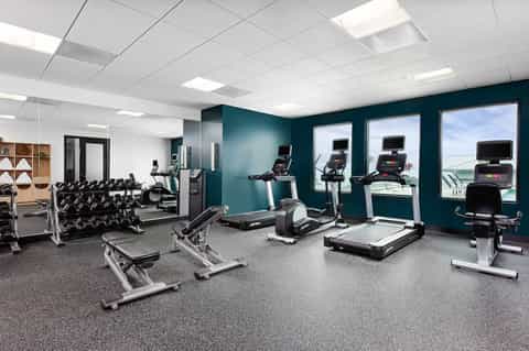 Modern fitness center with cardio equipment, treadmills, and teal accent walls