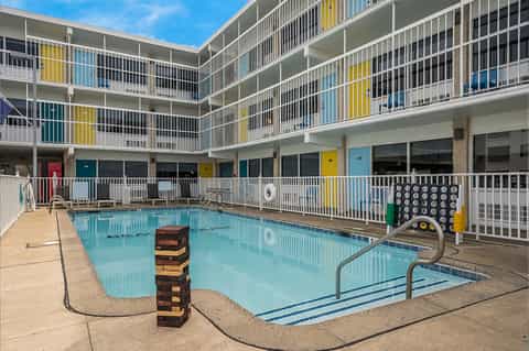 Indoor pool at retro hotel with colorful balconies, concrete deck, and ladder rails