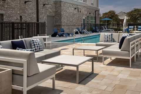 Rooftop pool deck with gray lounge seating, fire pit, modern residential building backdrop