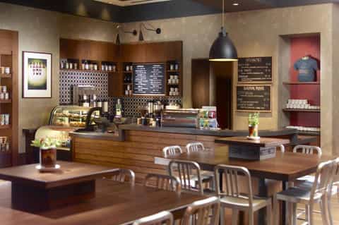 Contemporary coffee shop interior with wooden counter, black pendant light, menu boards, and café seating