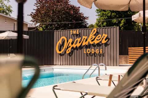 The Osbarker Lodge poolside sign with lounge chairs and swimming pool visible