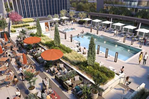 Rooftop resort with multiple pools, lounge seating with orange umbrellas, and surrounding high-rise buildings