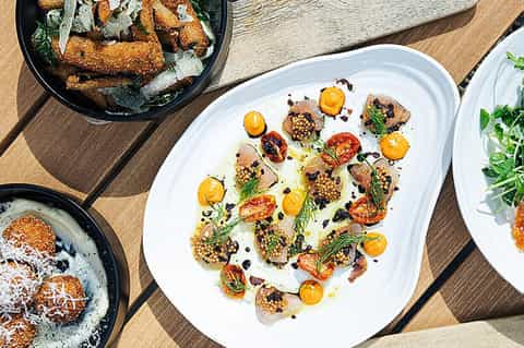 Overhead view of gourmet appetizers on white plate with colorful vegetables and garnish