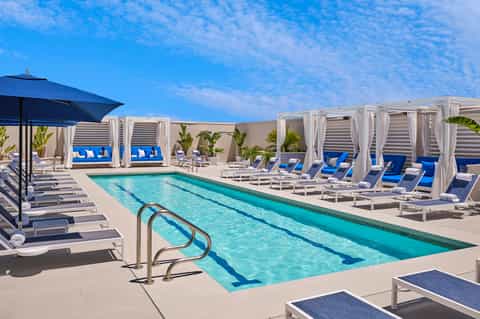 Outdoor resort pool with blue lounge chairs and white cabanas