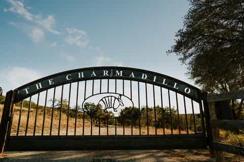 Black ornate gate entrance to The Charmadillo equestrian property with horse logo