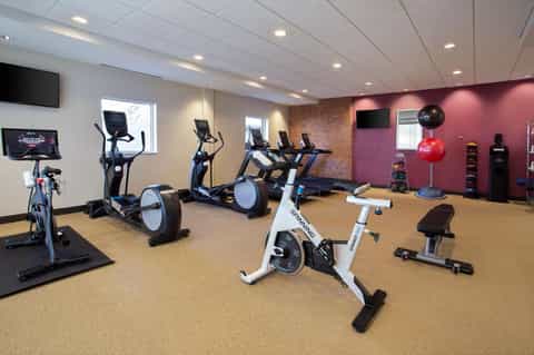 Modern fitness center with stationary bikes, ellipticals, treadmill, and pink accent wall