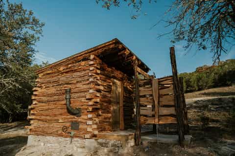 Historic log cabin with wooden fence structure in natural landscape setting