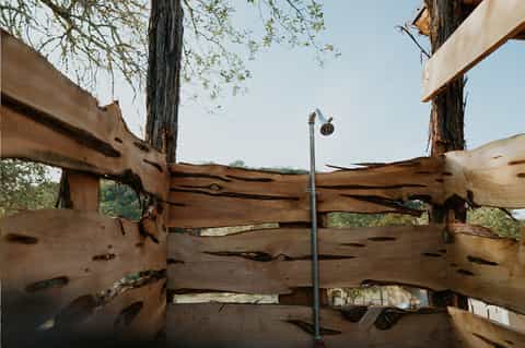 Wooden ranch fence with weathered beams and metal post against hillside landscape