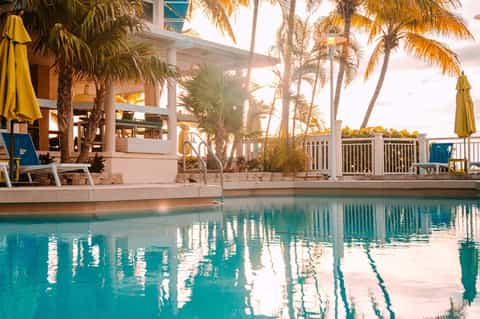 Palm-lined pool deck with lounge chairs and yellow umbrellas at waterfront property
