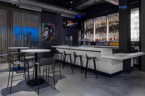 Contemporary bar lounge with black interior, white bar counter, mood lighting, and colorful artwork