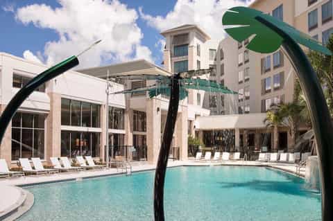 Modern resort pool deck with turquoise water, white lounge chairs, and contemporary architecture