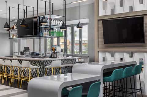 Contemporary bar lounge with suspended black pendant lights, patterned backsplash, and curved counter seating