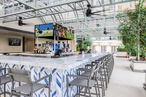 Modern outdoor bar with white marble counter, blue and white décor, and glass ceiling