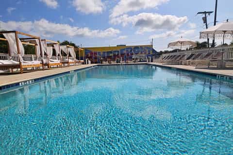 Resort swimming pool with cabanas, umbrellas, and beachfront setting