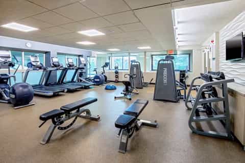 Bright fitness facility with treadmills, weight benches, and Reebok equipment