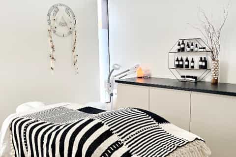 Minimalist bedroom with striped black and white bedding, dream catcher wall art, and modern furnishings