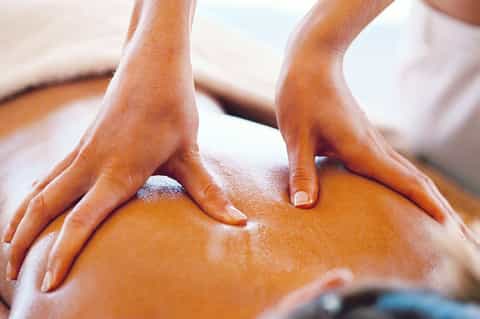Spa therapist performing massage treatment on client's back