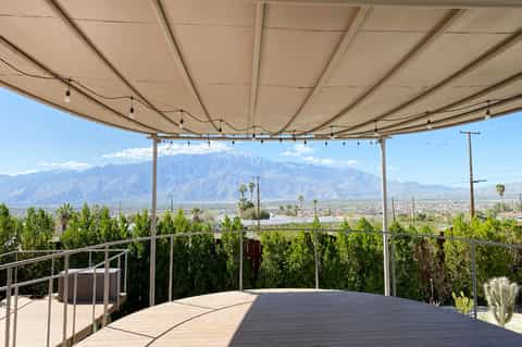 Desert mountain vista from rooftop terrace with shade structure, lounge seating, and scenic valley views