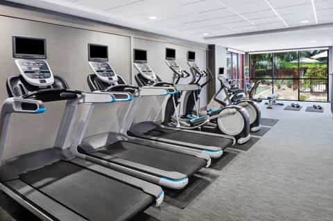 Modern fitness center with treadmills, elliptical machines, and stationary bikes with mounted screens