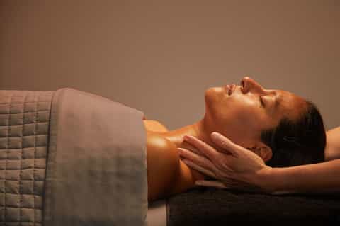 Spa therapist performing neck massage on relaxed client in warm lighting