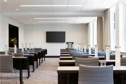 Modern conference room with gray seating arranged in rows and wall-mounted TV