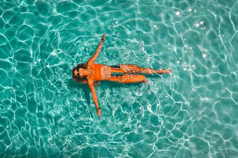 Aerial view of woman floating in crystal-clear turquoise ocean water