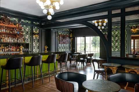 Upscale bar and lounge with green geometric walls, gold accents, and modern lighting