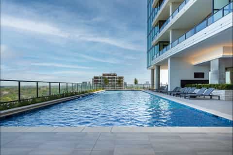 Modern rooftop infinity pool overlooking city skyline with lounge chairs and glass railings