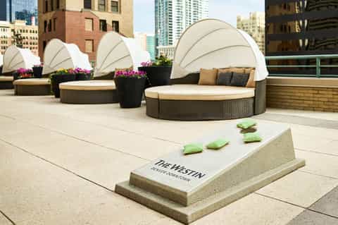 Rooftop terrace with white canopy cabanas, colorful flowers, and city skyline at The Westin