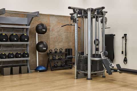 Modern fitness center with exercise equipment, weight racks, and TRX suspension training