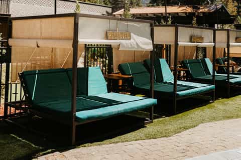 Resort cabanas with turquoise cushions, tan canvas privacy screens, and manicured lawn setting