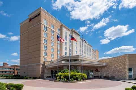 Marriott hotel exterior with brick facade, entrance, flags, and manicured landscaping