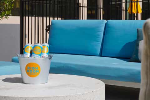 Poolside lounge area with blue cushioned seating, concrete table, and black railing