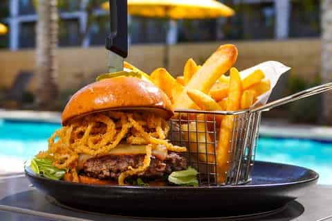 Gourmet burger with crispy fries served poolside at a resort restaurant