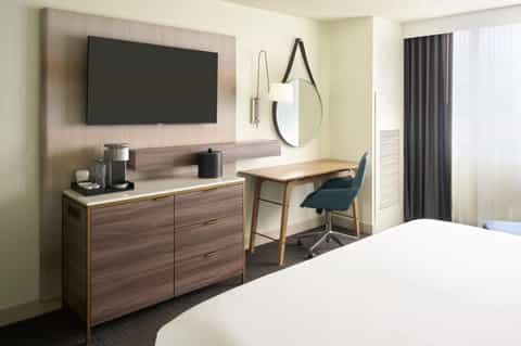 Modern hotel room with television, desk, work chair, and contemporary furnishings