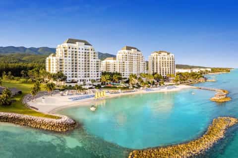 Beachfront resort with cream-colored towers, turquoise water, and manicured grounds
